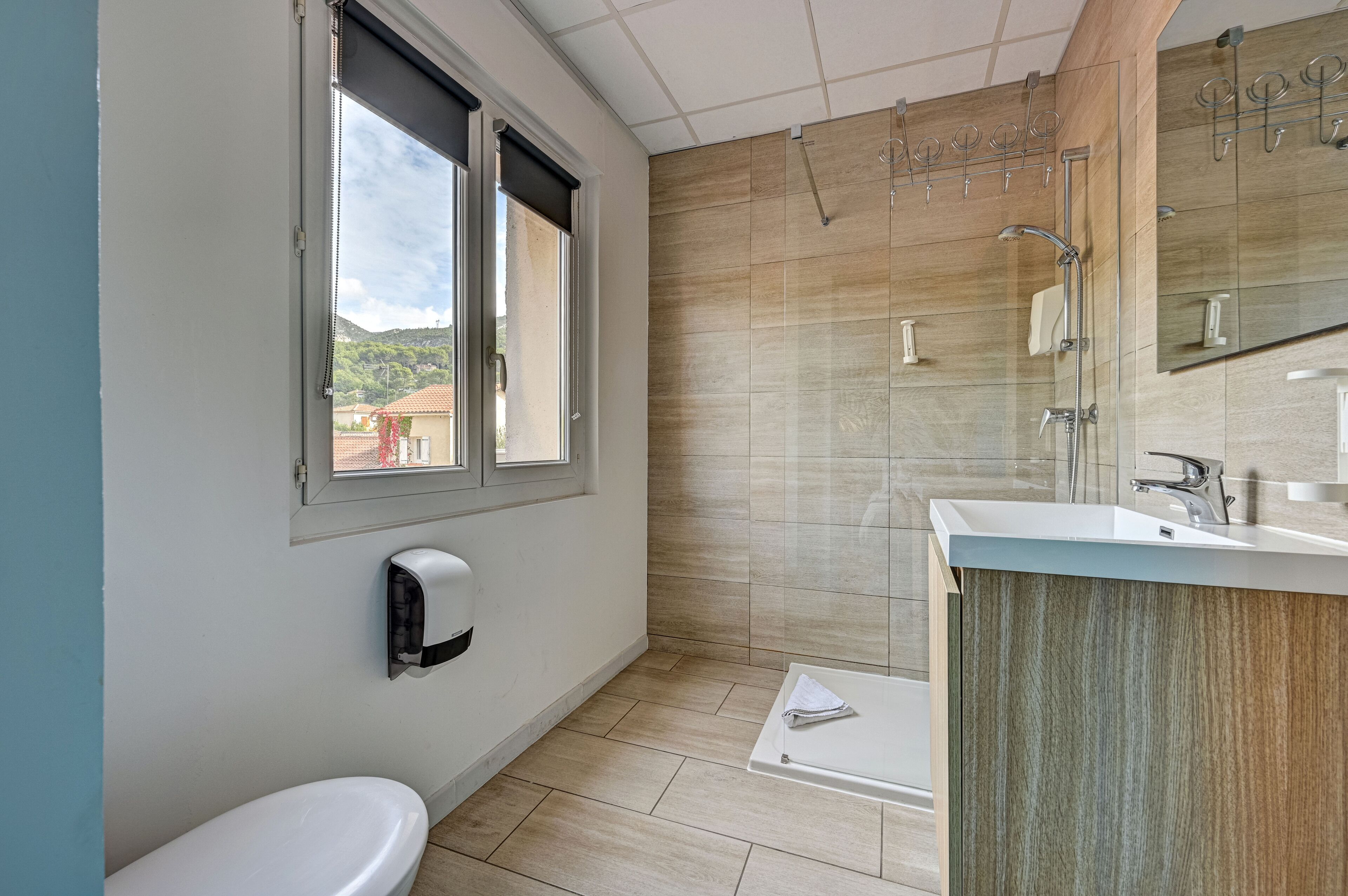 Ein modernes Badezimmer mit Toilette, Dusche, Waschbecken und einem Fenster.
