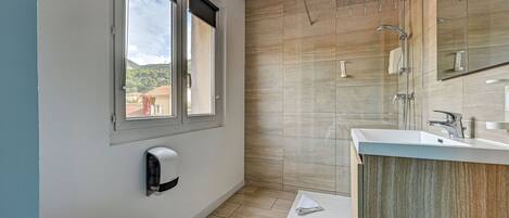 Ein modernes Badezimmer mit Toilette, Dusche, Waschbecken und einem Fenster.