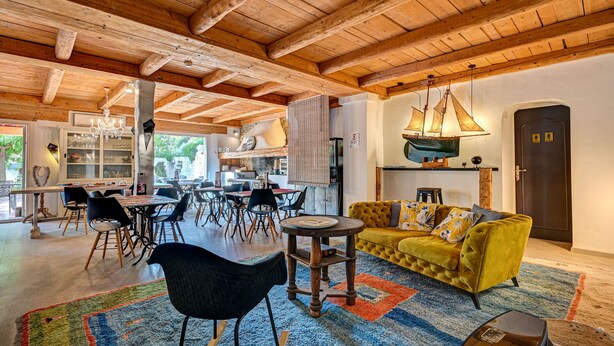 Un vaste espace de vie doté d’un plafond en bois, d’un canapé jaune et d’une table à manger avec des chaises.