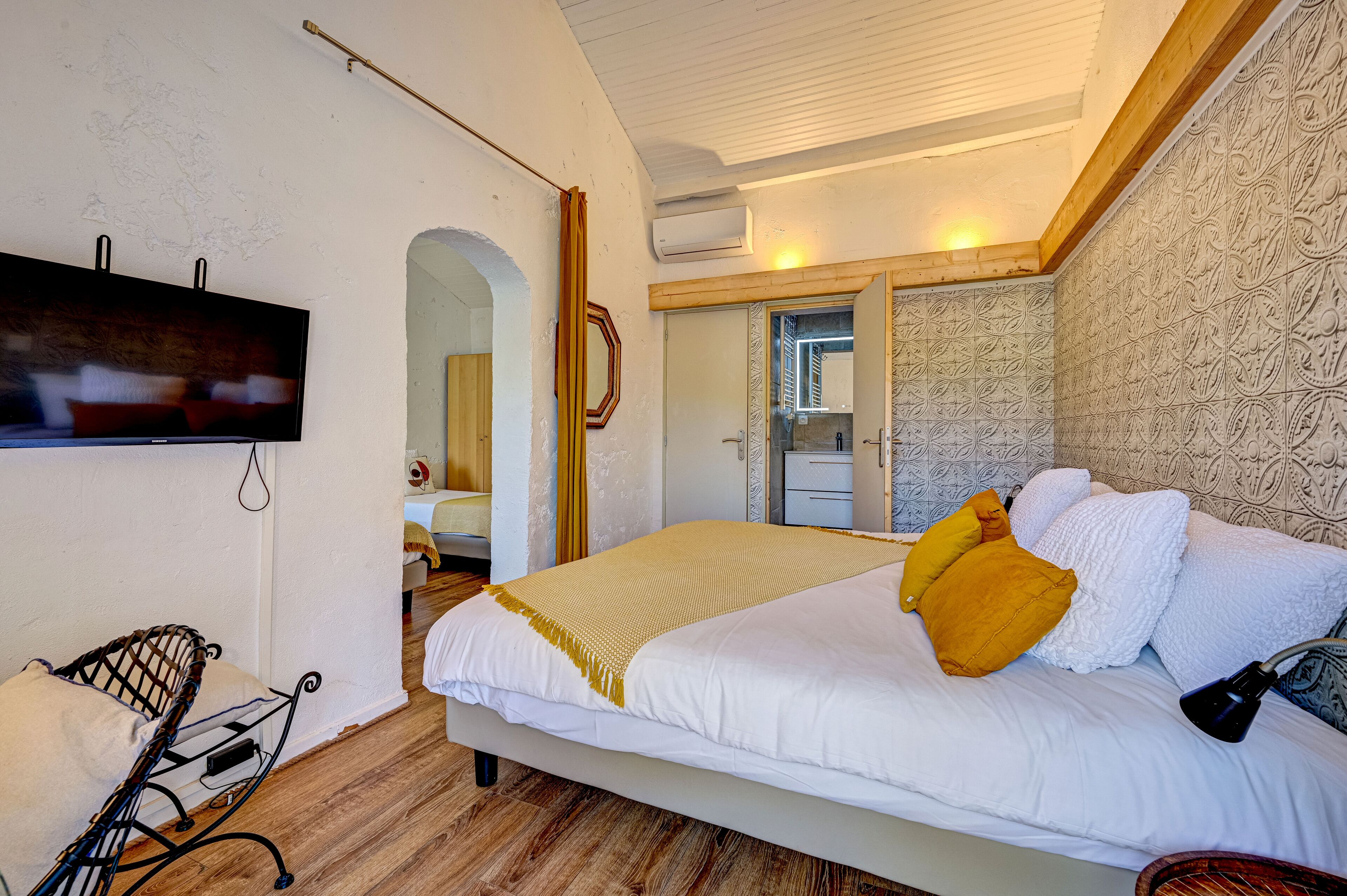 Une chambre à coucher avec un grand lit, une télévision, une chaise et une armoire.