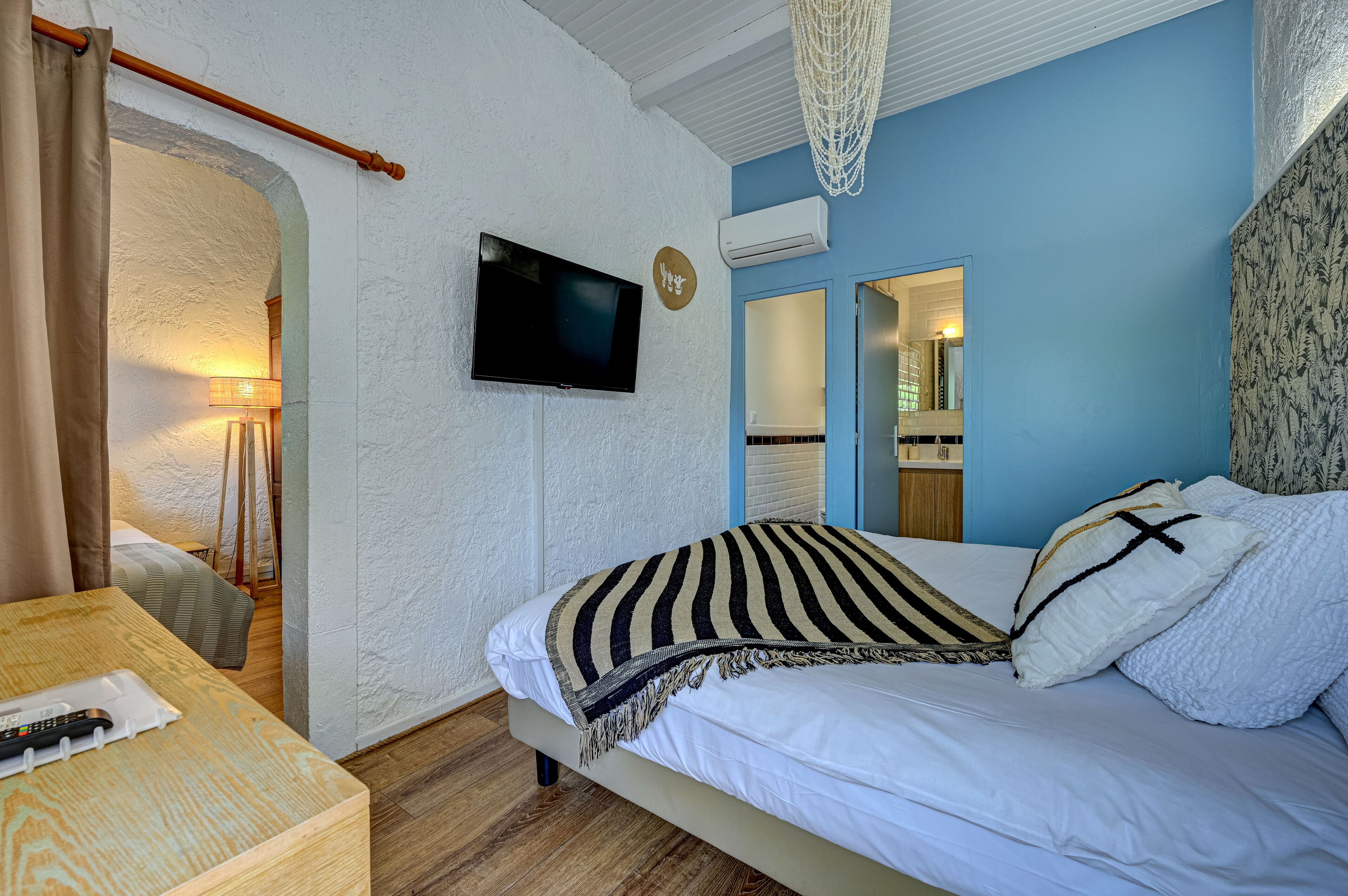 A bedroom with a bed, a television, and a wooden nightstand.