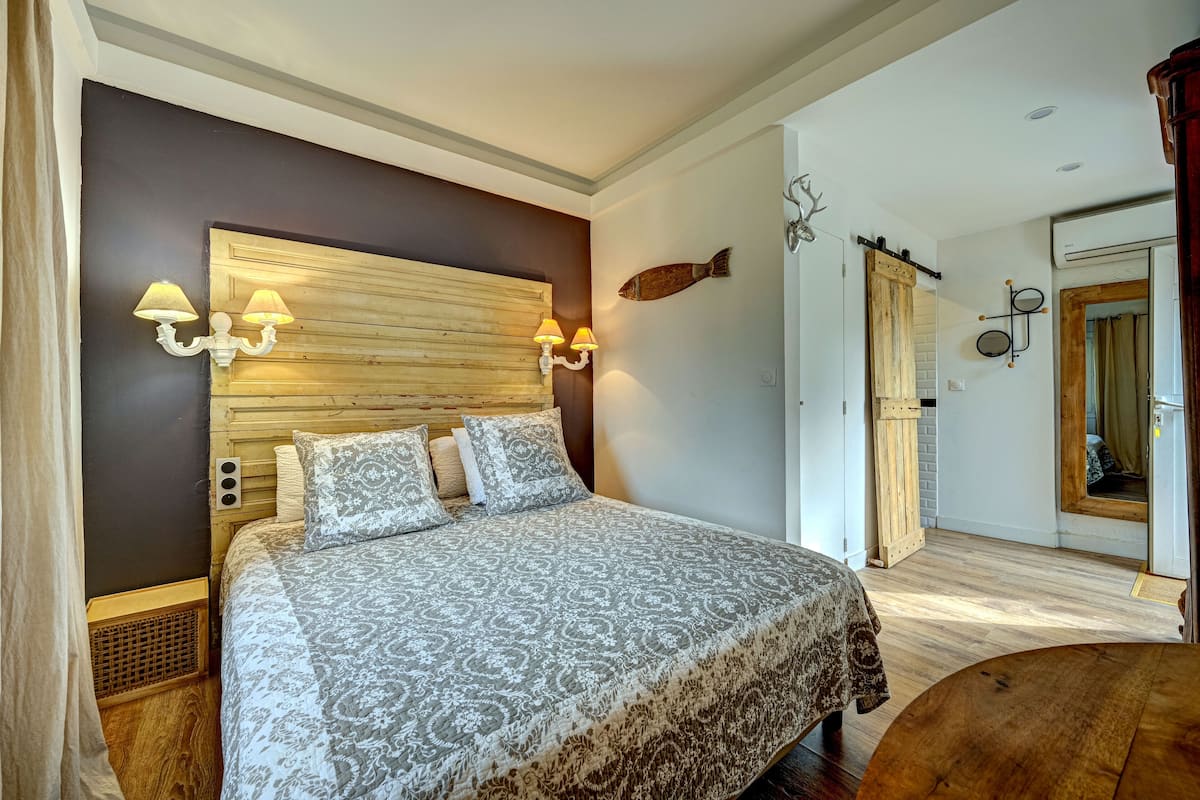 A bedroom with a large bed, wooden headboard, wall-mounted lamps, and a fish decoration.