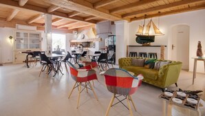 Un vaste espace de vie doté d’un haut plafond en bois, d’un canapé vert et d’une table à manger avec des chaises.