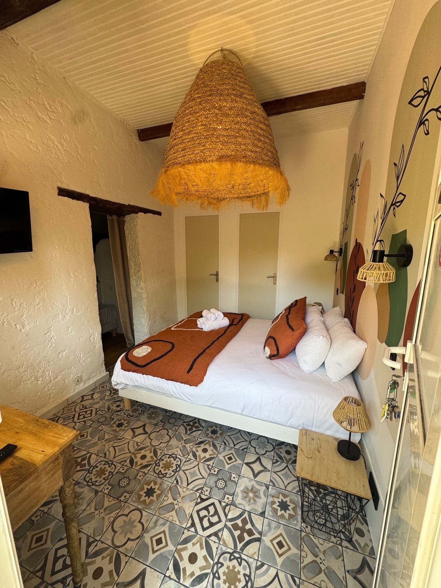 A cozy bedroom with a bed, a hanging basket, patterned tiles, and a small table.