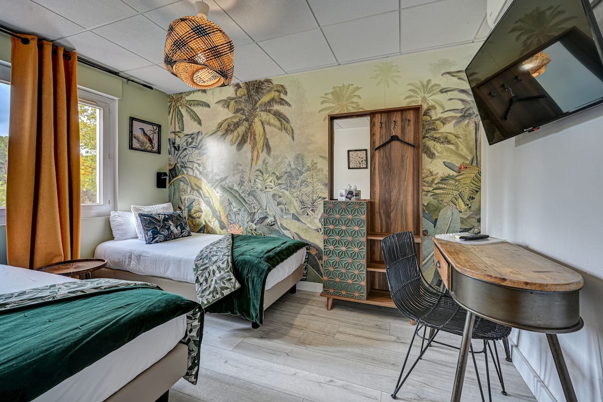 A room with two beds, a desk, and a TV.
