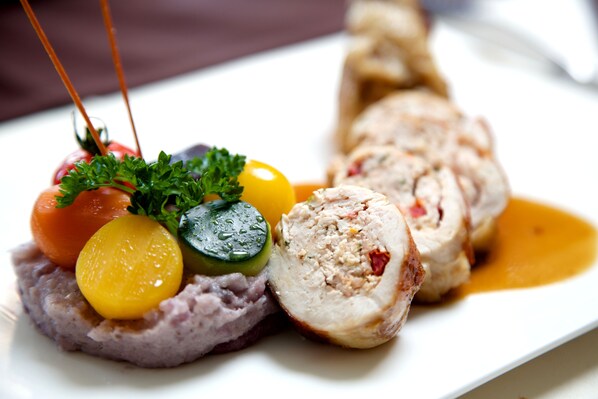 A plated dish with sliced meat, vegetables, and a sauce.
