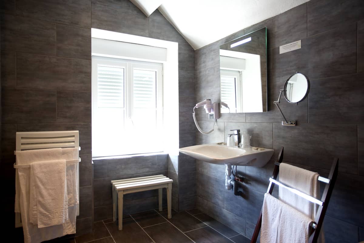 Un baño moderno con un ventanal grande, un lavamanos, un espejo y un perchero para toallas.