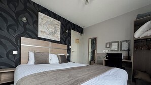 A hotel room with a large bed, a desk with a chair, a wardrobe, and a mirror. - Hostellerie du Centrotel et Spa (Montmarault)