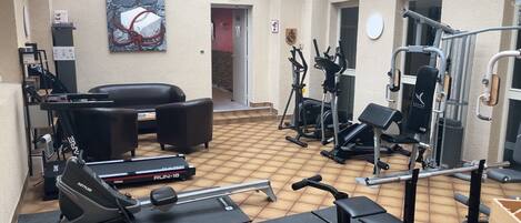 A gym with cardio machines, weightlifting equipment, and a seating area with a painting.