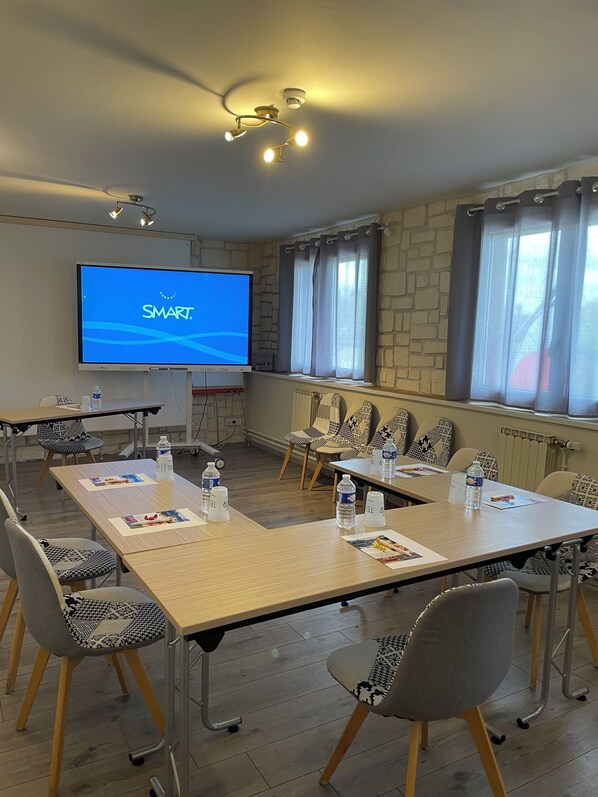 Une salle de conférence dotée d’un grand écran affichant le mot « SMART », une longue table entourée de chaises, ainsi que des bouteilles d’eau et des documents posés sur la table.