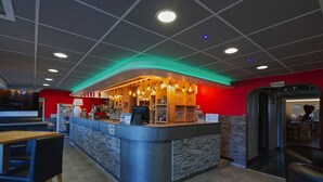 A modern bar area with a curved counter, seating, and a red accent wall. - Hostellerie du Centrotel et Spa (Montmarault)