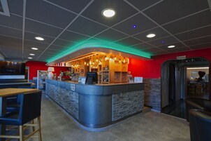 Uma área de bar moderna com balcão curvo, assentos e uma parede de destaque vermelha.