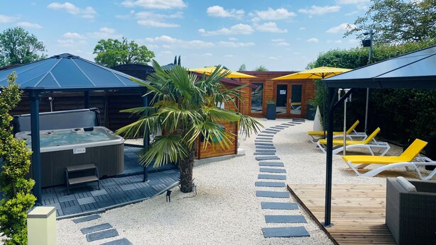 A patio area with a hot tub, lounge chairs, and a covered seating area. - Hostellerie du Centrotel et Spa (Montmarault)