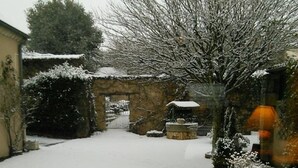 Un patio cubierto de nieve con paredes de piedra y una puerta.