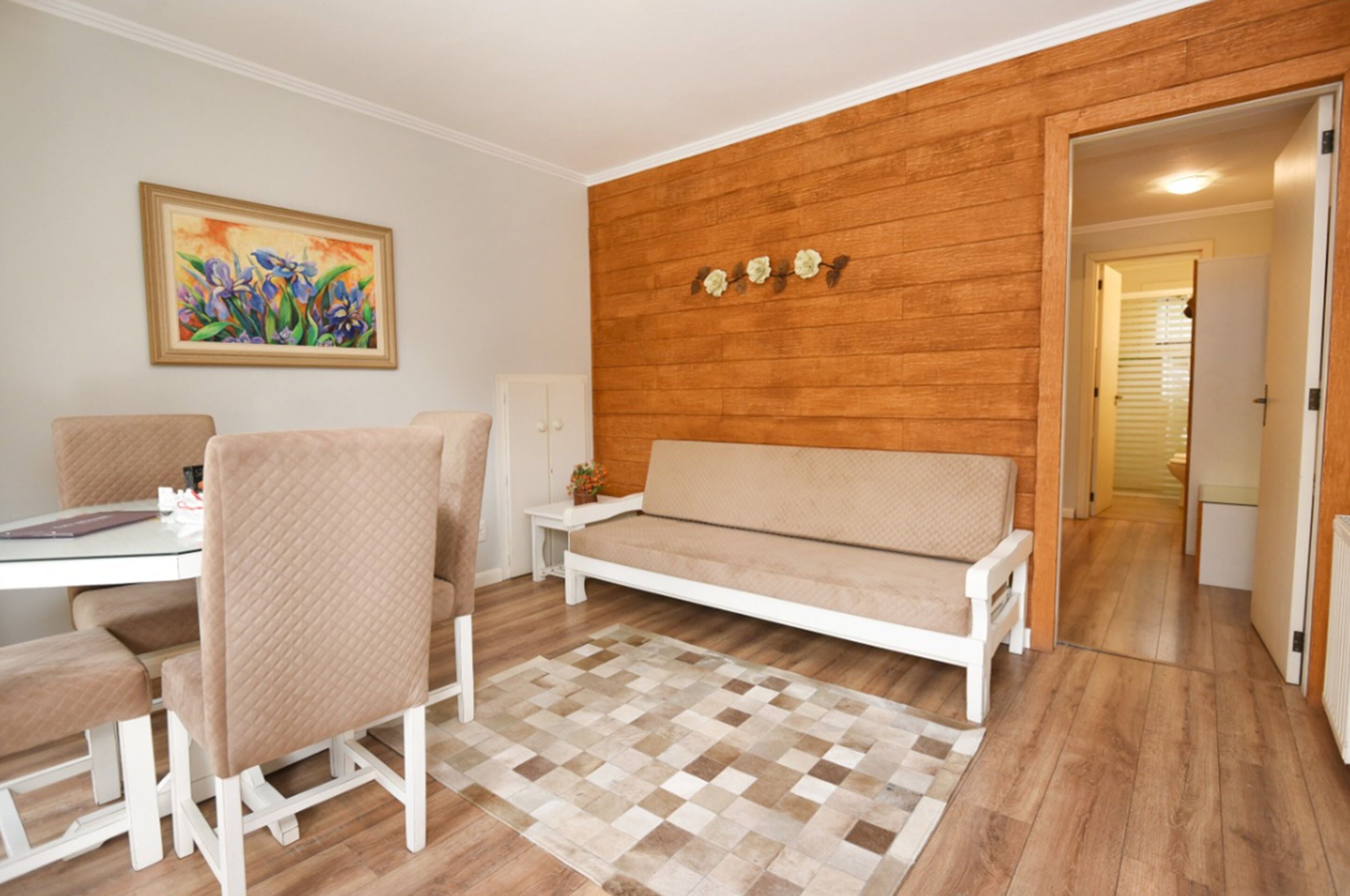 Un salon moderne comprenant un canapé, des fauteuils, une table à manger et un mur d’accent en bois.