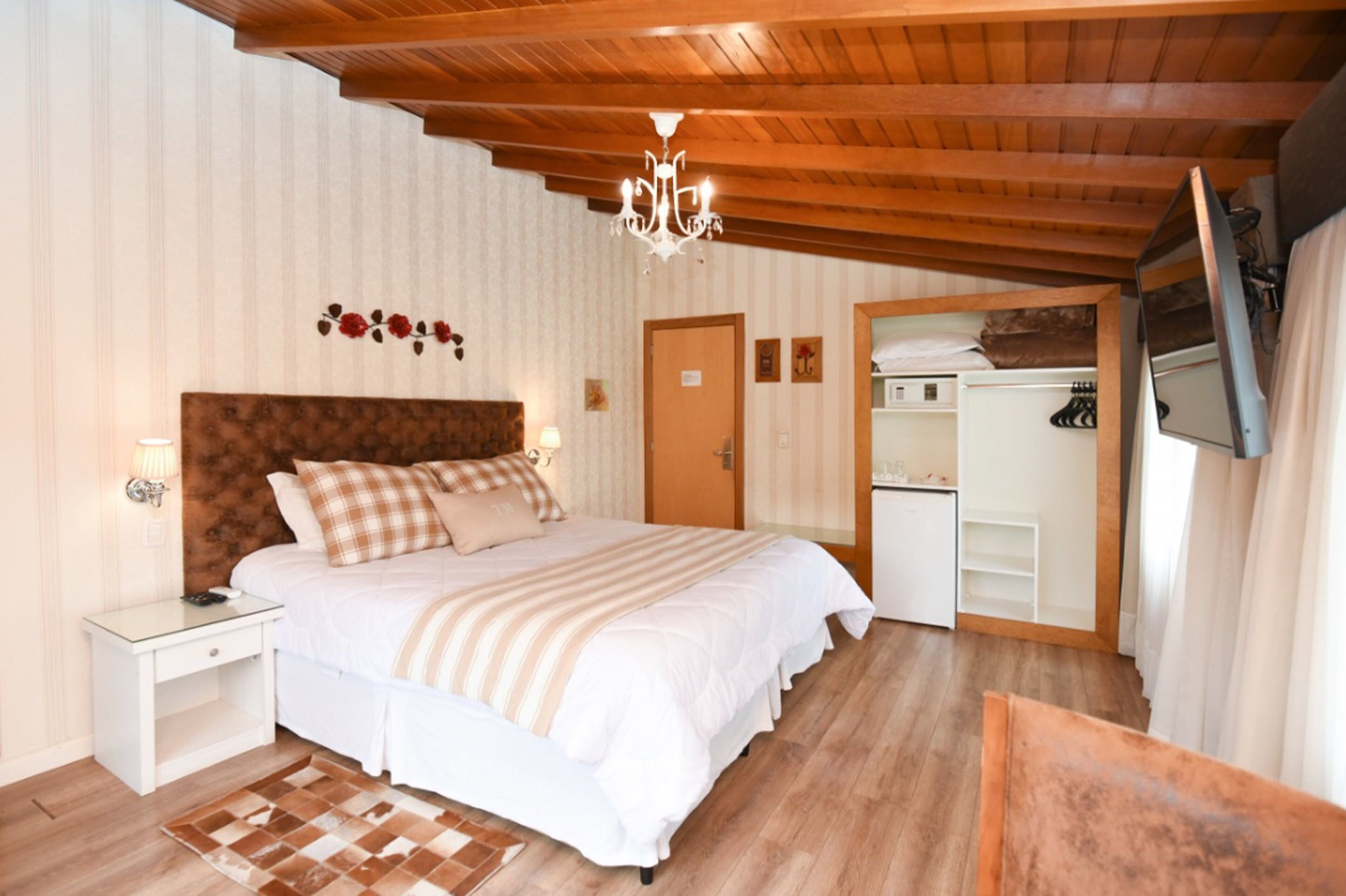 Ein Schlafzimmer mit Holzboden, einem Bett mit weißer Bettwäsche, einem Nachttisch, einer Kommode und einem Spiegel.