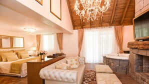 Amplia sala de estar con un sofá grande, una mesa de centro y una chimenea. Hay una mesa de comedor con sillas y un candelabro colgando del techo.