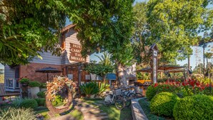 Un hotel con fachada de ladrillo, zona de estar al aire libre y un sendero jardín que lleva a la entrada.