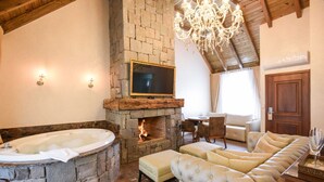 Una sala de estar acogedora con chimenea de piedra, un televisor grande, un sofá cómodo y una araña.