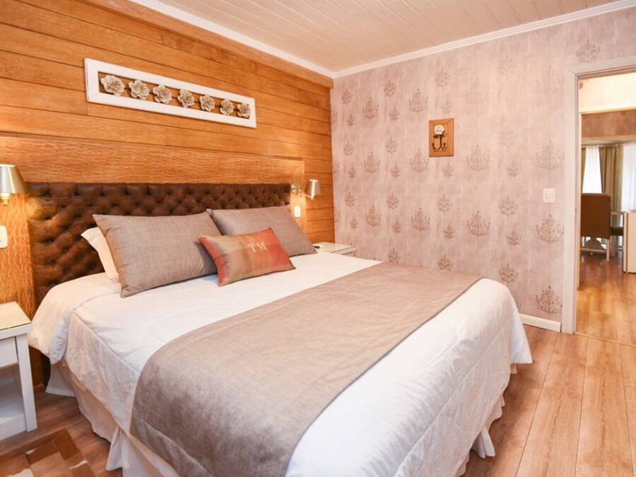 Ein Schlafzimmer mit Holzkopfstütze, einem großen Bett mit vielen Kissen, Nachttischlampen und einem Nachttisch.