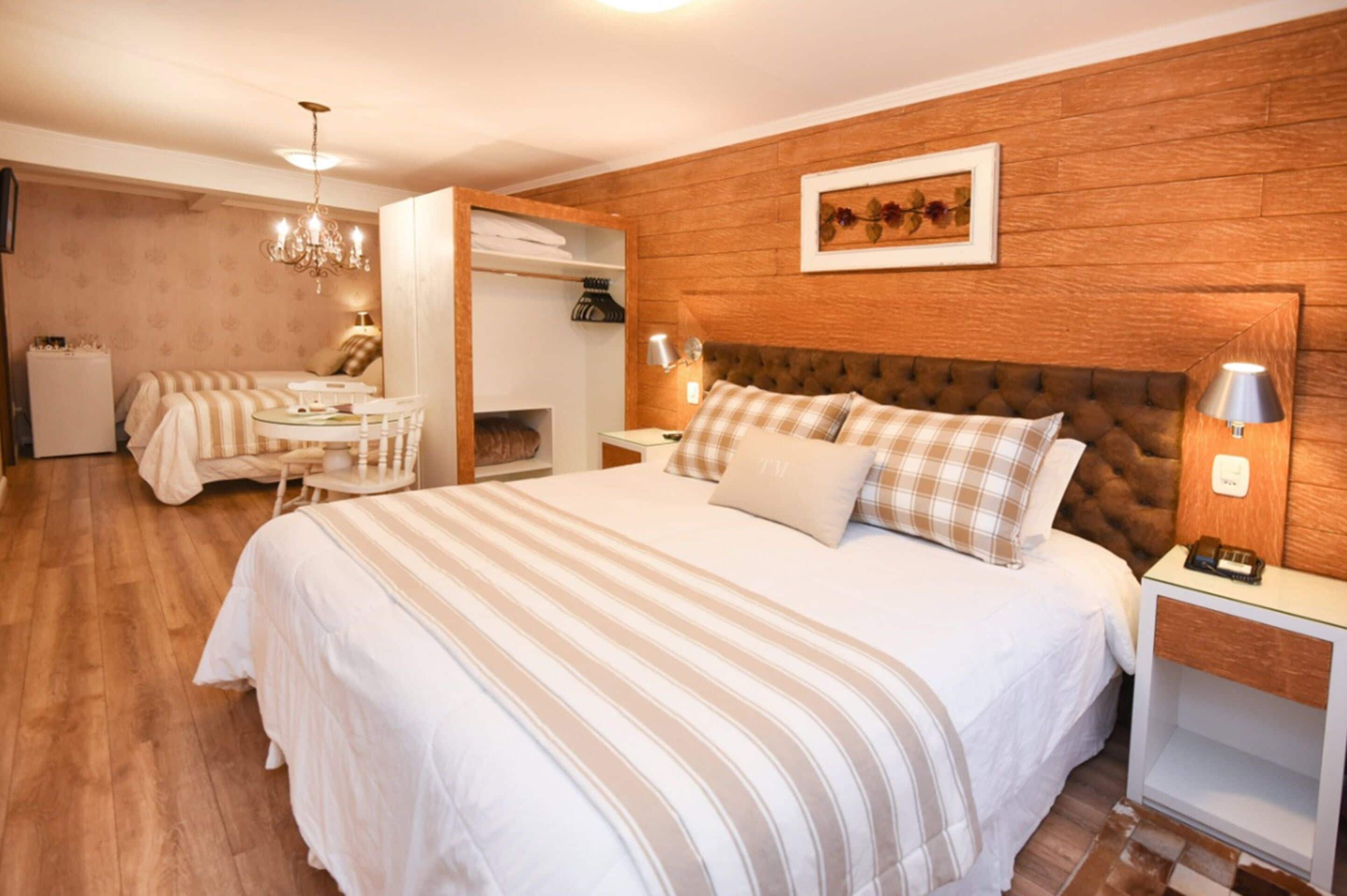 Habitación de hotel con una cama grande, cabecera de madera, un escritorio con silla y un armario.