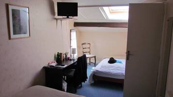A small room with two beds, a desk, a chair, a television, and a skylight.