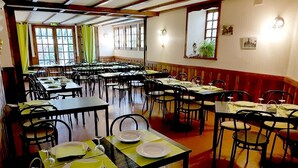 Un espace repas comprenant plusieurs tables et chaises, disposées dans un aménagement spacieux et agrémenté de grandes fenêtres laissant entrer la lumière naturelle.