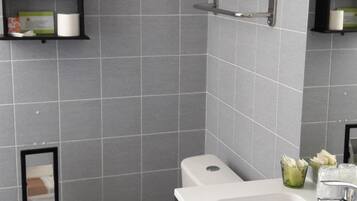 A modern bathroom with grey tiles, a black toilet, a white sink, and a mirror above the sink.