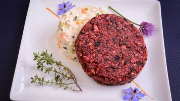 A square plate with a round meat patty and a side of mashed potatoes.