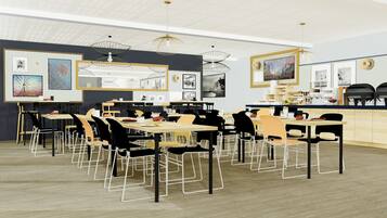 A modern dining area with multiple tables and chairs, framed artwork on the walls, and pendant lighting.