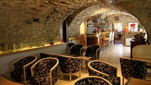 A cozy interior with stone walls, a bar area, and seating with floral upholstery. - Hôtel le Chêne Vert (Rocher)