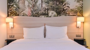 A hotel room with a large bed, two bedside tables with lamps, a wooden headboard, and a tropical-themed mural on the wall. - Hôtel le Chêne Vert (Rocher)
