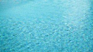 A swimming pool with clear water and yellow lounge chairs in the background. - Hôtel le Chêne Vert (Rocher)