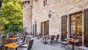 Un café al aire libre con paredes de piedra, mesas y sillas de madera.
