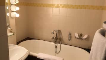 A bathroom with a bathtub, a sink, and a mirror with lights.