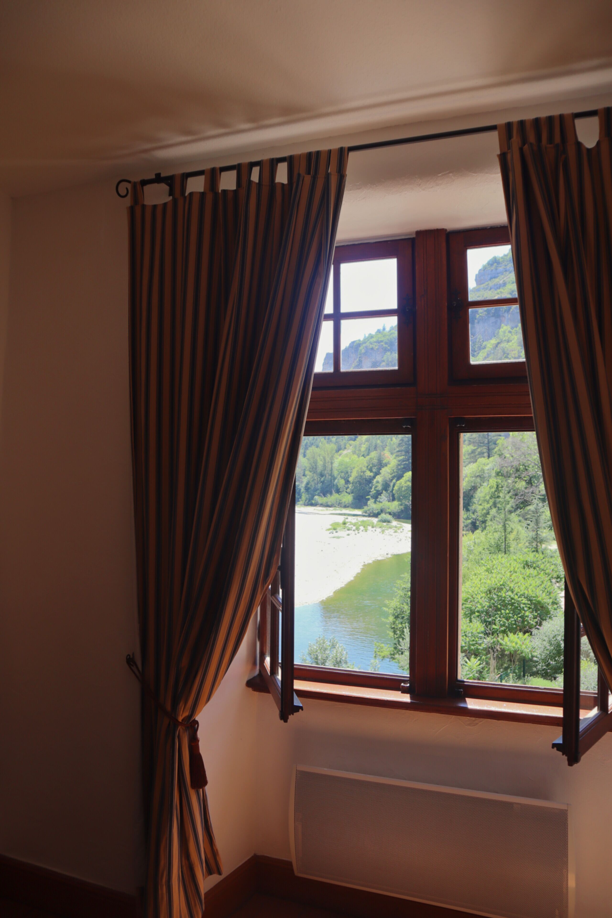 A room with a large window overlooking a forested area and a body of water.