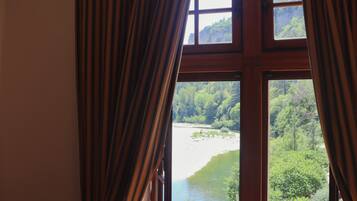 A room with a large window overlooking a forested area and a body of water.
