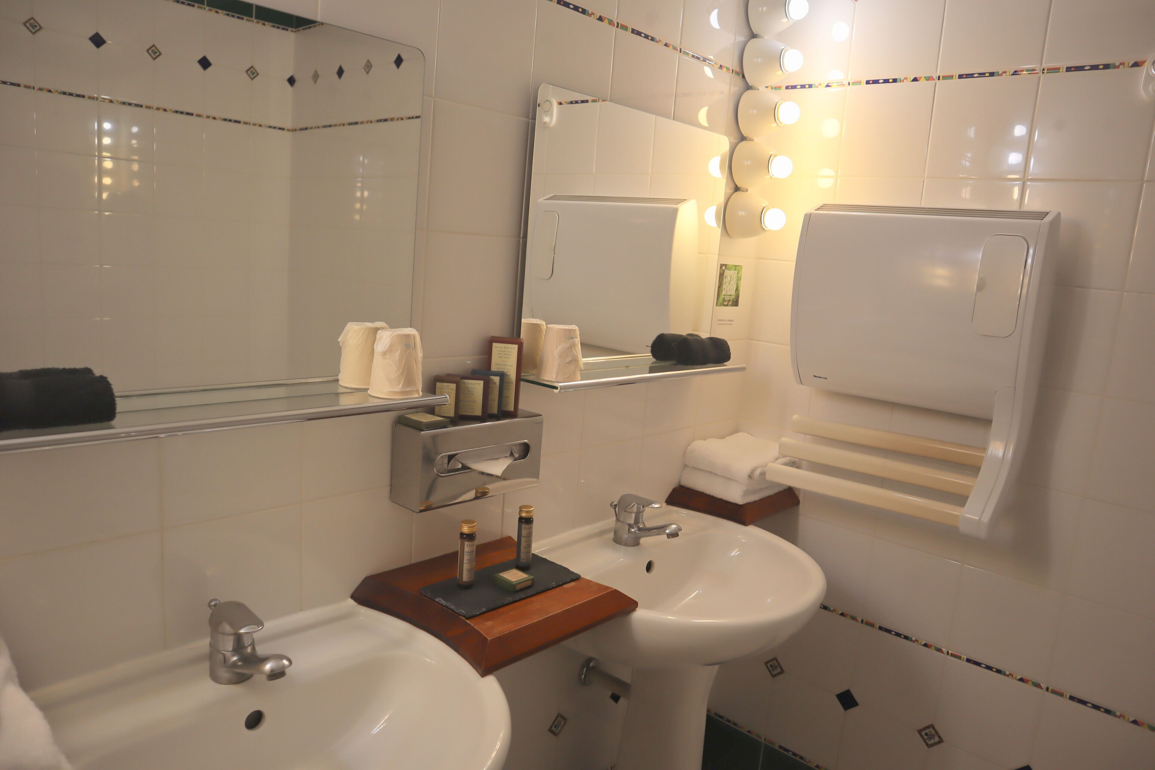 Un bagno con due lavandini, uno specchio e un porta asciugamani.