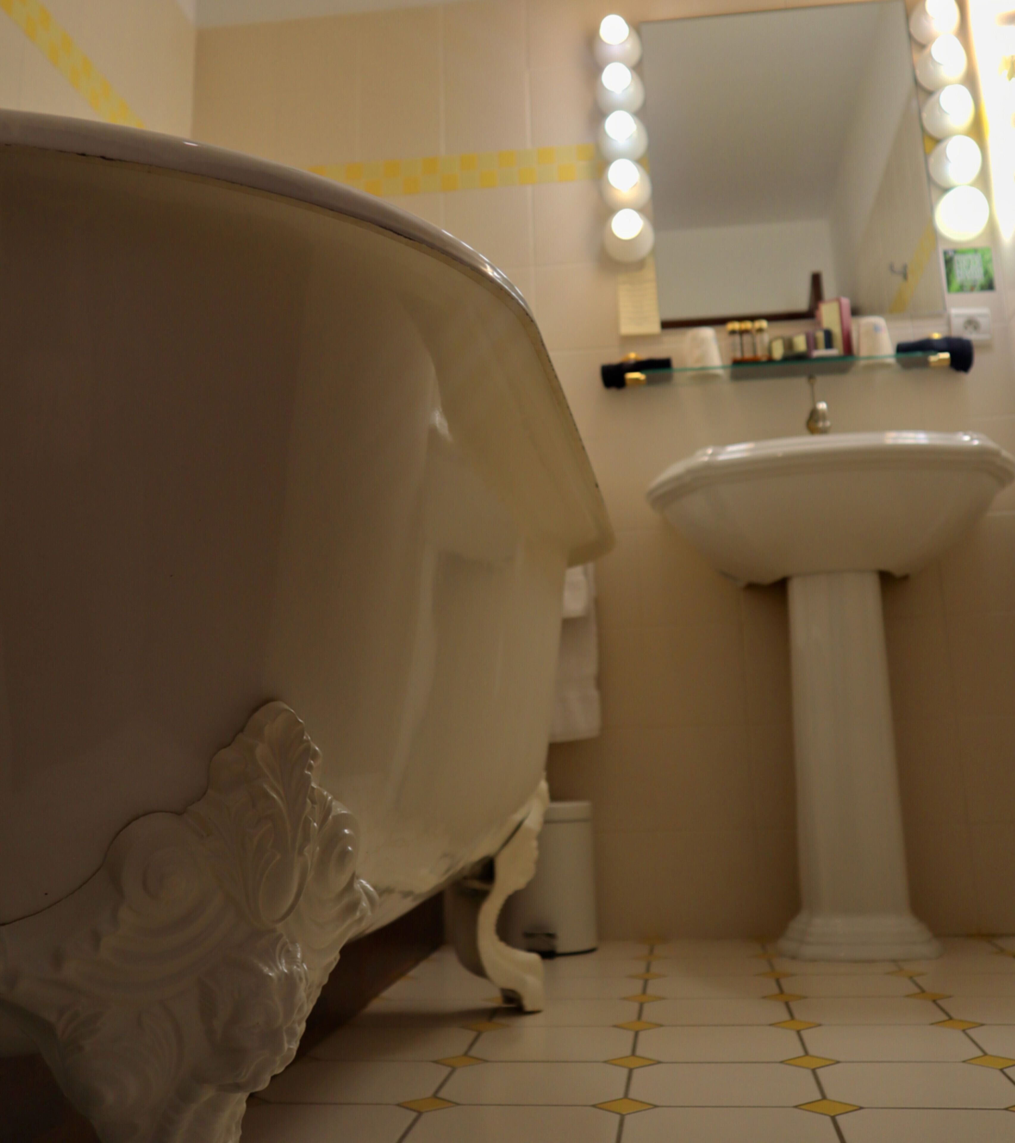 A bathroom with a bathtub, a sink, and a mirror with lights.