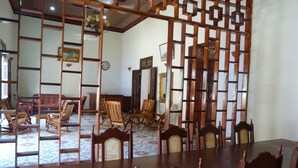 Un espace repas comprenant une longue table et de nombreuses chaises, un paravent décoratif en bois et un sol à motifs.