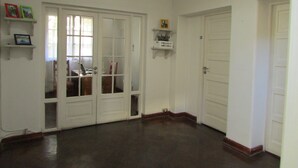A hallway with white doors, a wooden floor, and a ceiling light. - Casa Provence (Santiago)