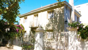 A two-story building with a balcony, a gated entrance, and potted plants. - Casa Provence (Santiago)