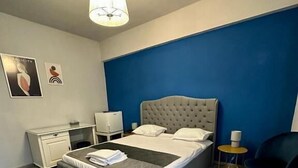 A bedroom with a bed, bedside table, chair, and a lamp.