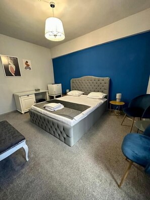 A bedroom with a bed, bedside table, chair, and a lamp.