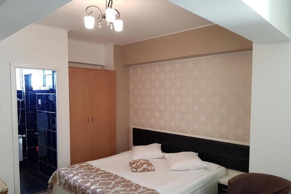 A bedroom with a bed, a wardrobe, a chair, and a patterned wall.