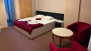 A hotel room with a bed, a small table, a chair, and a wardrobe.