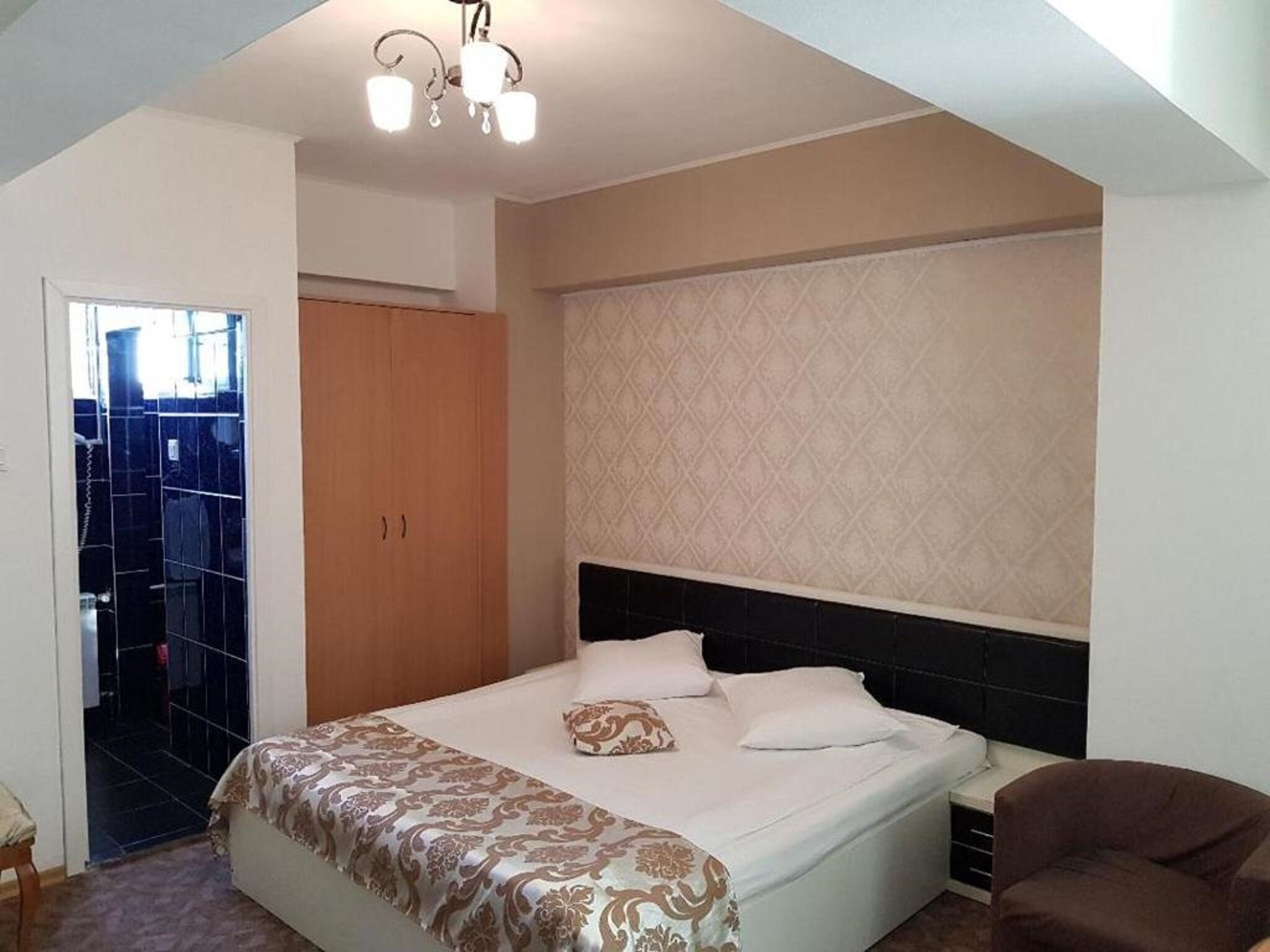 A bedroom with a bed, a wardrobe, a chair, and a patterned wall.