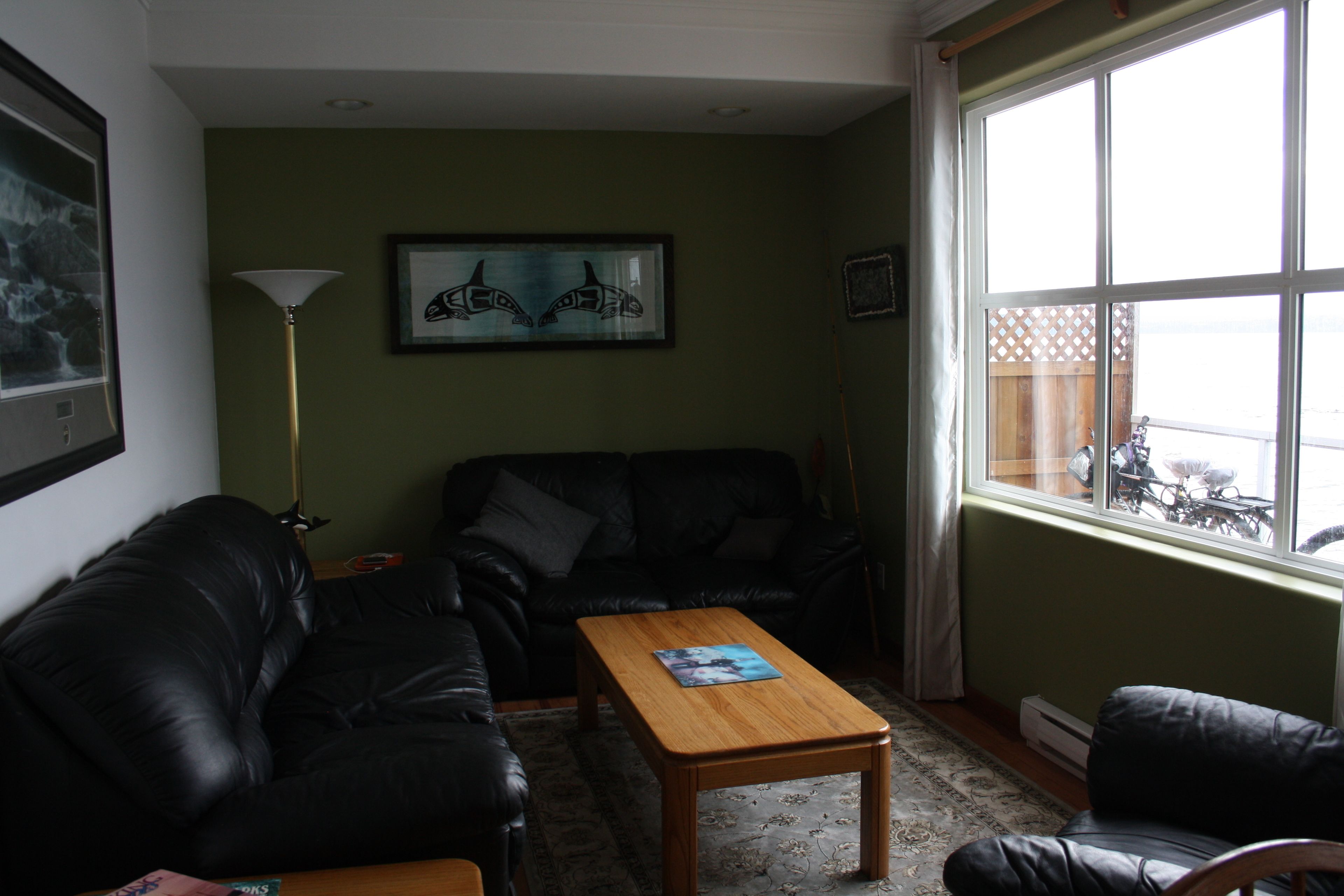 A living room with a black leather sofa, a wooden coffee table, and a framed artwork on the wall.