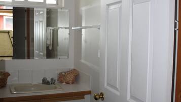A bathroom with a white door, a mirror, a sink, and a towel rack.
