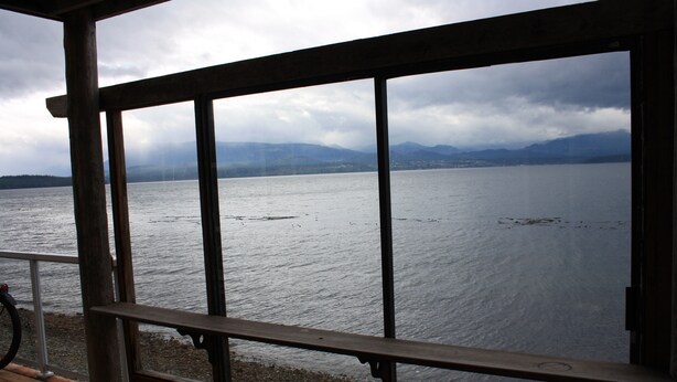 Une terrasse en bois offrant une vue sur un lac et des montagnes.